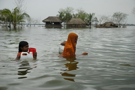 Mother and child wade through flood water in search of safe drinking water, at the cyclone Aila affected area in Koira, Khulna, Bangladesh. May 25, 2009. Cyclone Aila struck the coastal areas of Bangladesh on May 25, causing severe damage to crops, homes and lives.